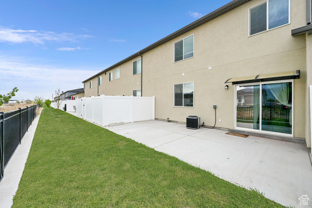 Back of house featuring a patio, stucco siding, a fenced backyard, cooling unit, and a lawn