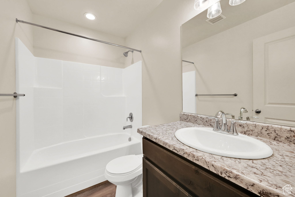 Full bath featuring toilet, wood finished floors, bathing tub / shower combination, visible vents, and vanity