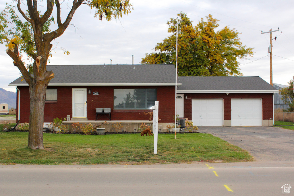 Single story home featuring a front yard, brick siding, driveway, and a garage