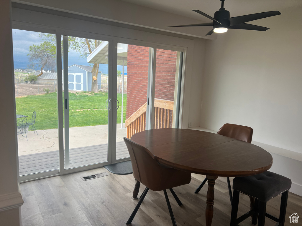 Dining space with a ceiling fan, visible vents, and wood finished floors