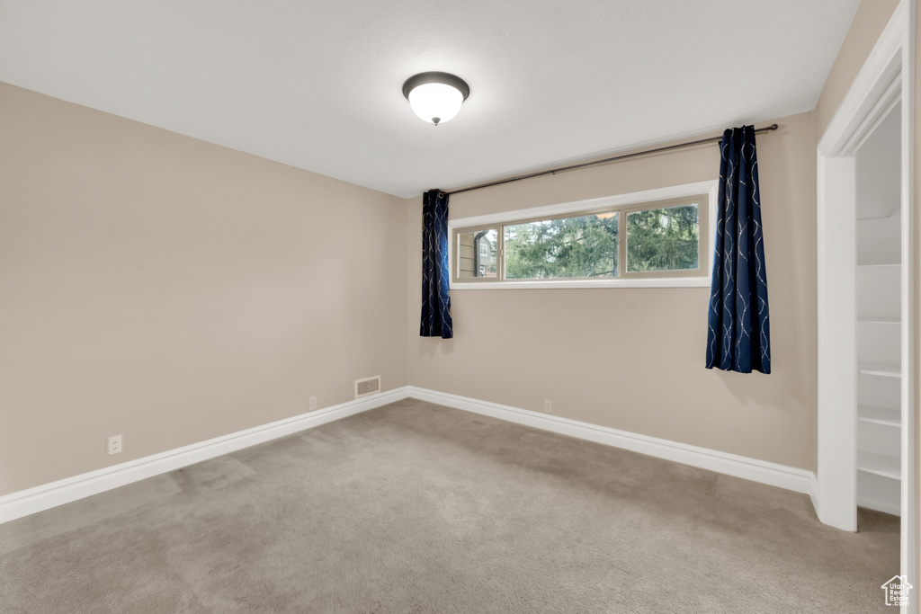Unfurnished room featuring baseboards, visible vents, and carpet