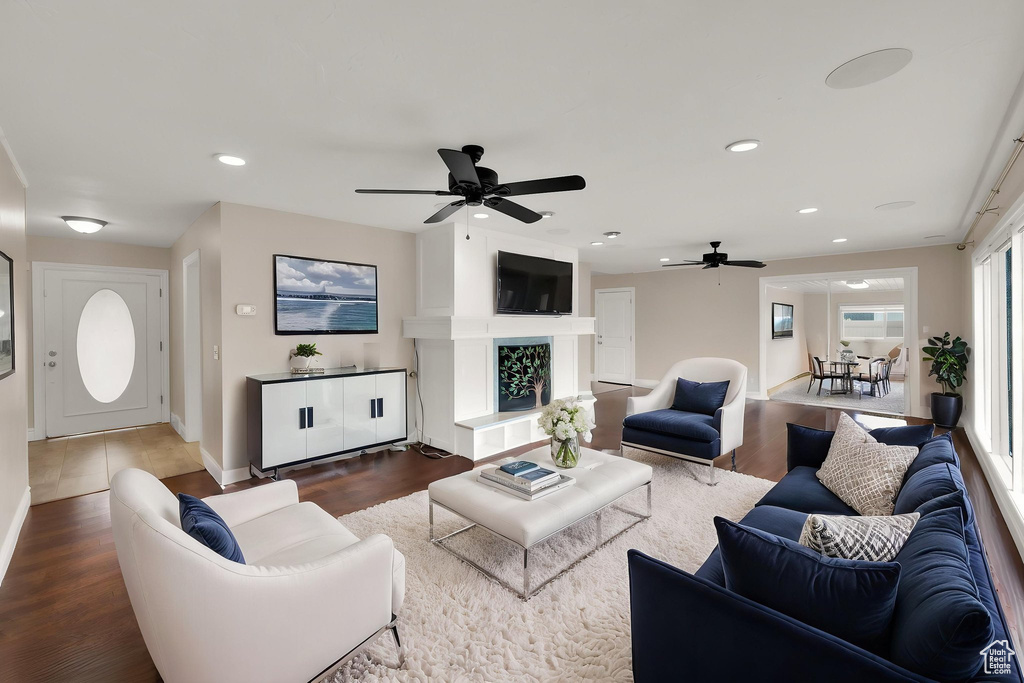 Living room with dark wood-type flooring, a ceiling fan, baseboards, and recessed lighting