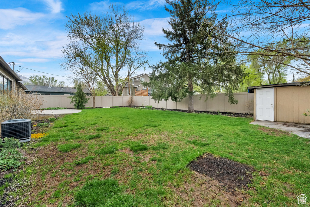View of yard featuring central air condition unit, an outbuilding, and a fenced backyard