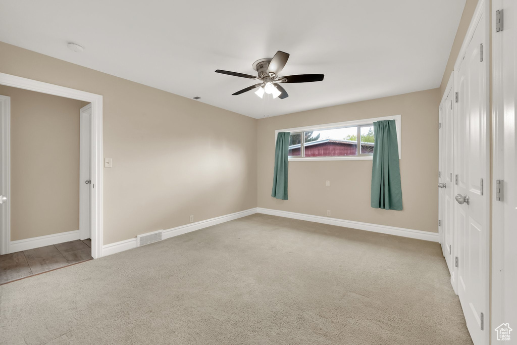 Unfurnished bedroom with baseboards, a ceiling fan, visible vents, and carpet