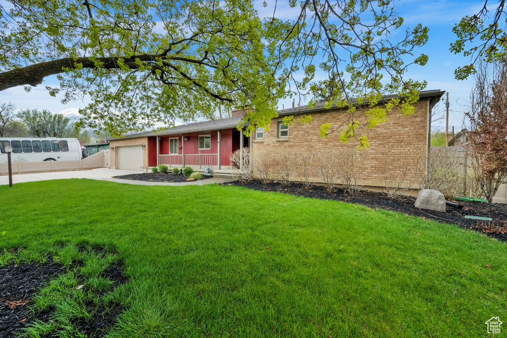 Ranch-style house with a front lawn, concrete driveway, fence, brick siding, and an attached garage