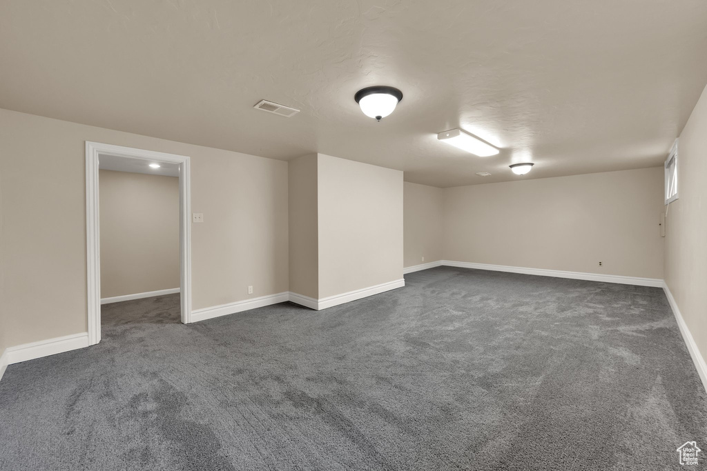 Basement featuring dark carpet, baseboards, and visible vents