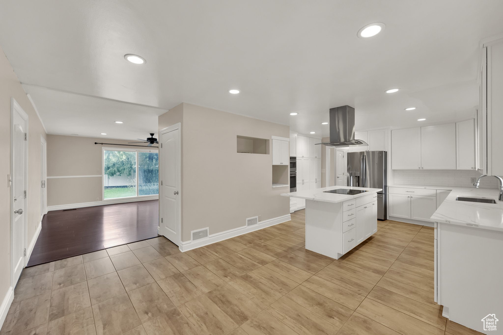 Kitchen featuring recessed lighting, island exhaust hood, visible vents, a sink, and a center island with sink