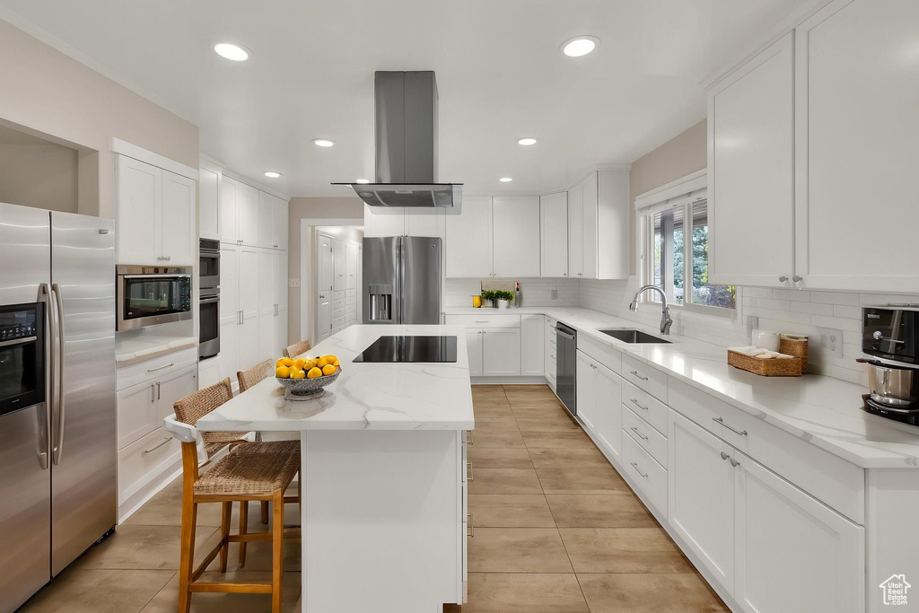 Kitchen with a center island, island exhaust hood, a sink, appliances with stainless steel finishes, and light tile patterned floors