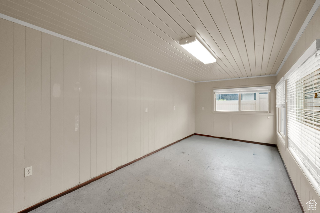 Unfurnished room featuring wooden ceiling, concrete floors, and crown molding