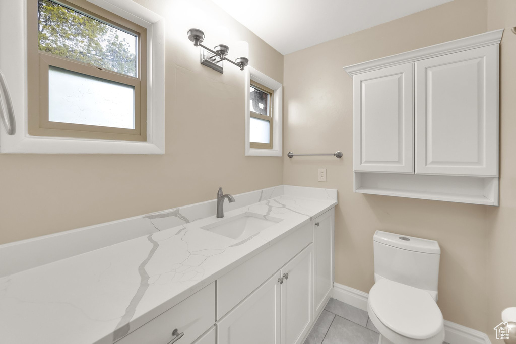 Bathroom featuring baseboards, vanity, tile patterned floors, and toilet