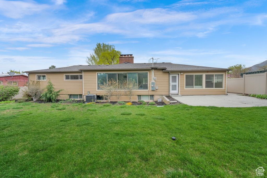 Back of house featuring fence, a lawn, central AC, and a patio
