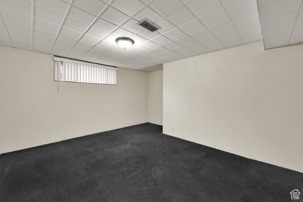 Below grade area featuring dark carpet, a paneled ceiling, and visible vents