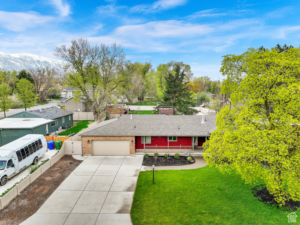 Ranch-style house featuring fence, a front lawn, concrete driveway, covered porch, and a garage