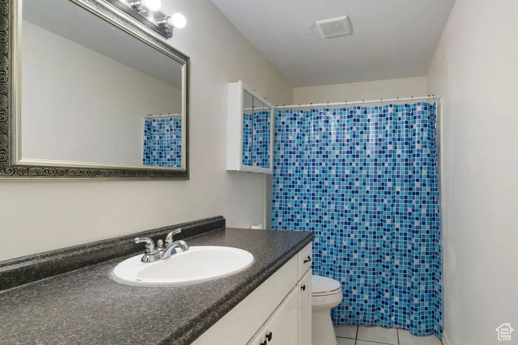 Full bath with a shower with curtain, tile patterned flooring, and toilet