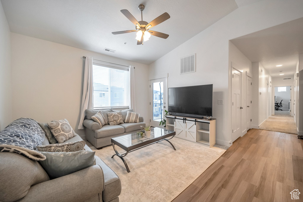 Living area with vaulted ceiling, a ceiling fan, light wood-style floors, and visible vents