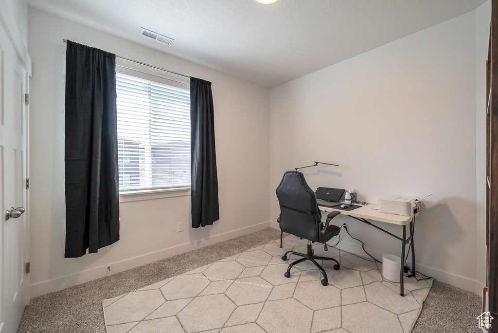 Office featuring light colored carpet, baseboards, a healthy amount of sunlight, and visible vents