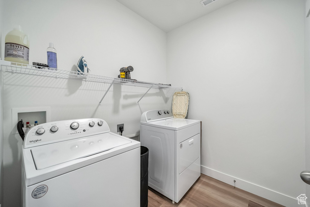 Laundry area featuring laundry area, visible vents, washing machine and dryer, light wood-type flooring, and baseboards