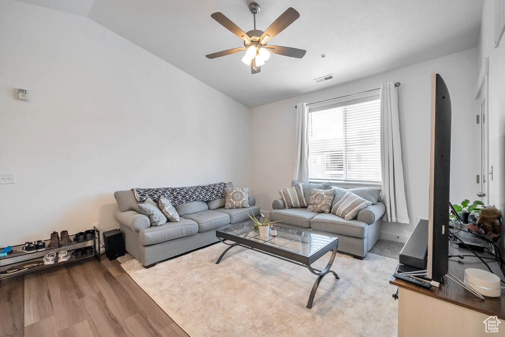 Living room featuring ceiling fan, lofted ceiling, light wood-style floors, and visible vents
