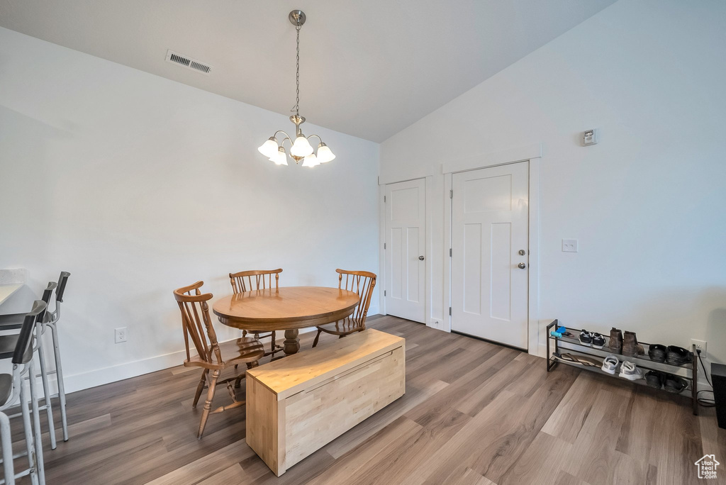 Dining space featuring lofted ceiling, wood finished floors, a chandelier, and visible vents
