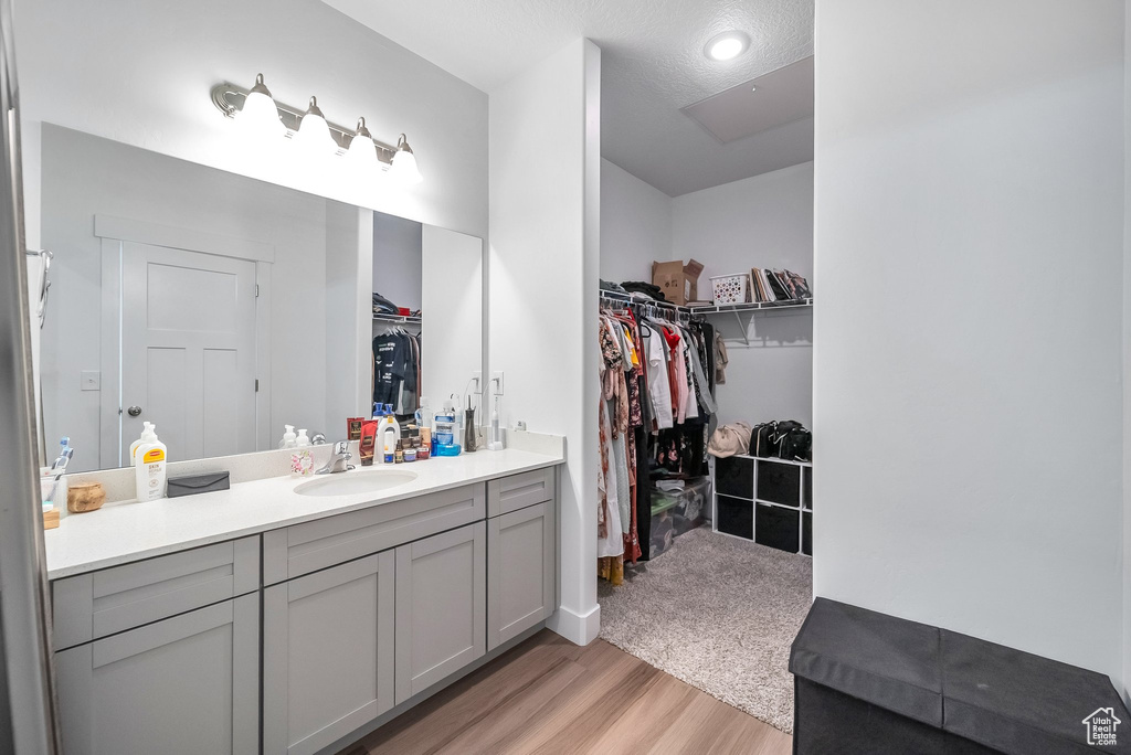 Bathroom with recessed lighting, wood finished floors, a spacious closet, and vanity