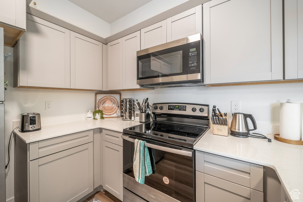 Kitchen featuring appliances with stainless steel finishes and light stone counters