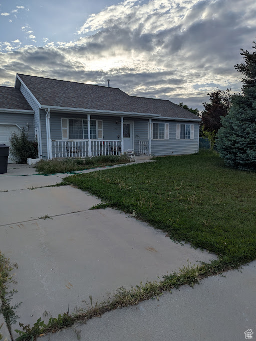 Ranch-style house with a porch, a front lawn, and a shingled roof