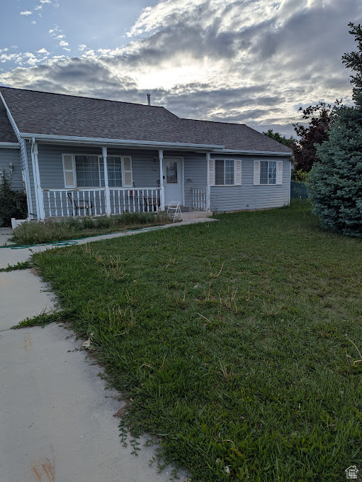 Ranch-style house with covered porch, a front yard, and a shingled roof