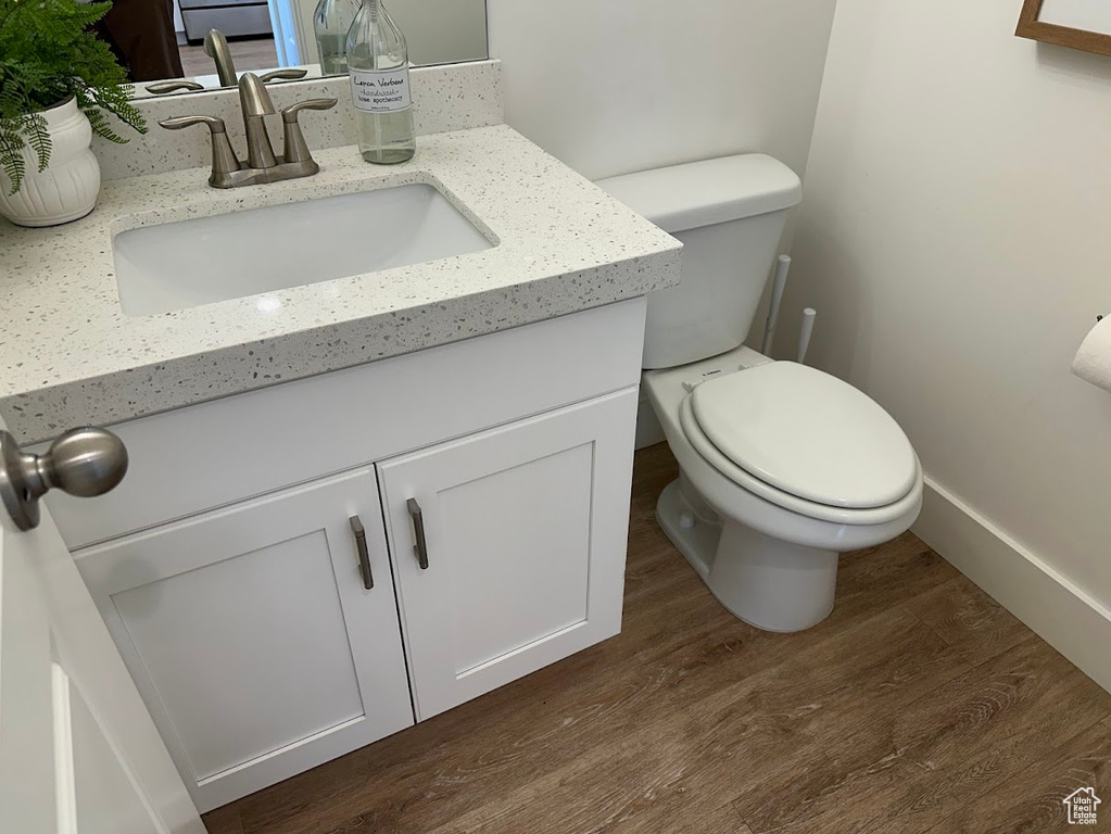 Bathroom featuring wood finished floors, vanity, toilet, and baseboards