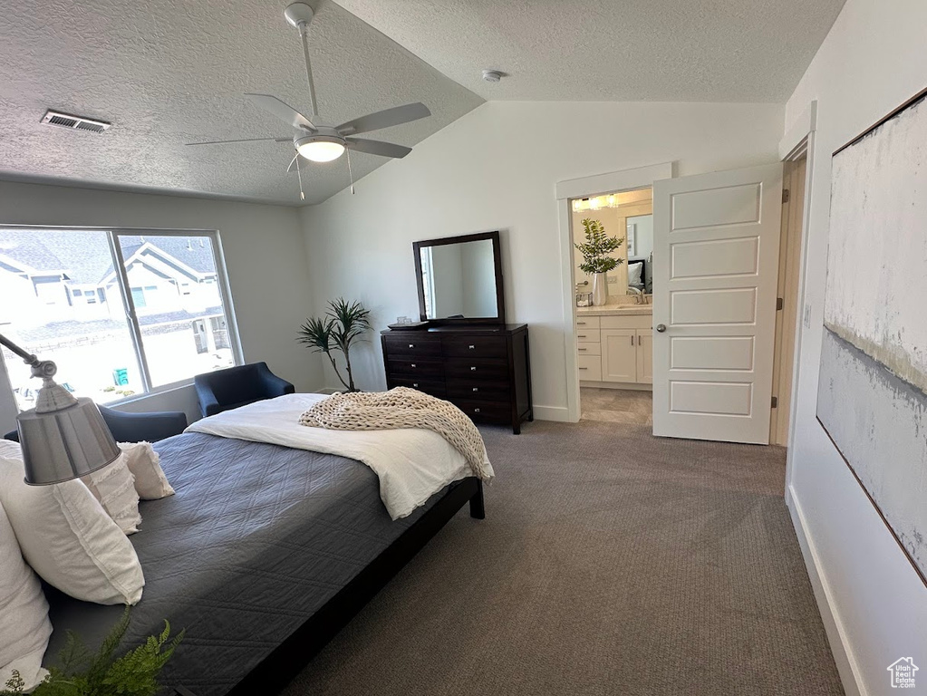 Carpeted bedroom with vaulted ceiling, visible vents, baseboards, a textured ceiling, and ensuite bathroom