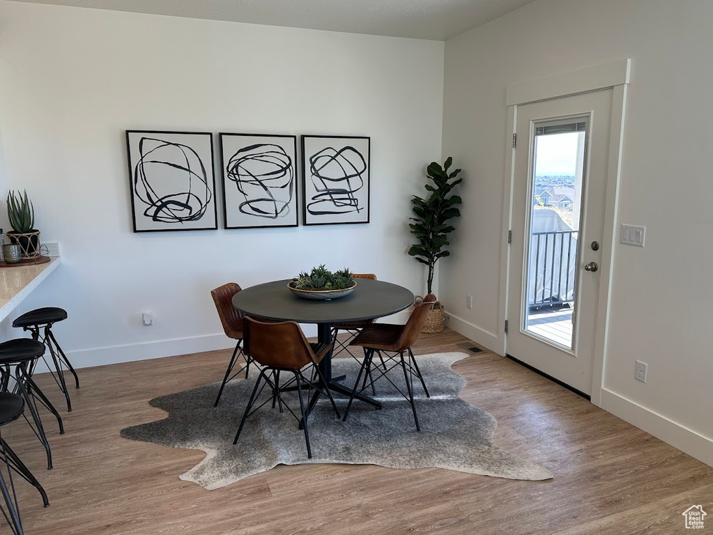 Dining space with wood finished floors, visible vents, and baseboards
