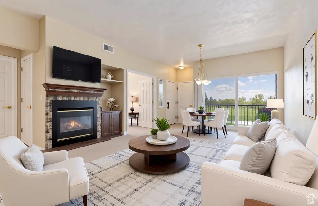 Carpeted living area featuring a healthy amount of sunlight, a chandelier, a stone fireplace, and visible vents