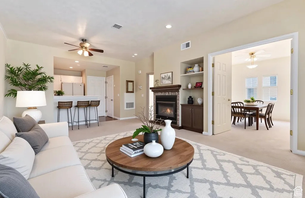 Living room featuring visible vents, a ceiling fan, built in features, and light carpet