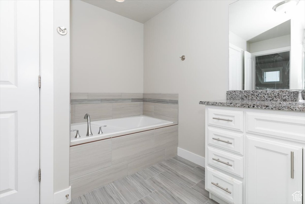 Bathroom featuring vanity, a garden tub, and baseboards