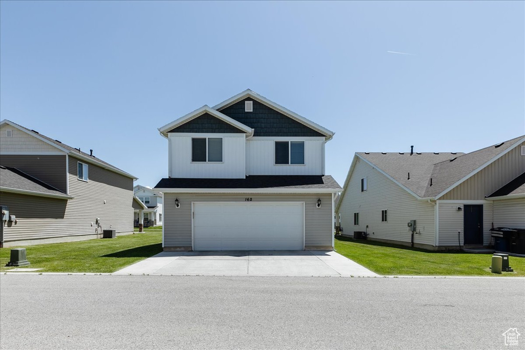 View of front of property with driveway, an attached garage, central AC, and a front lawn