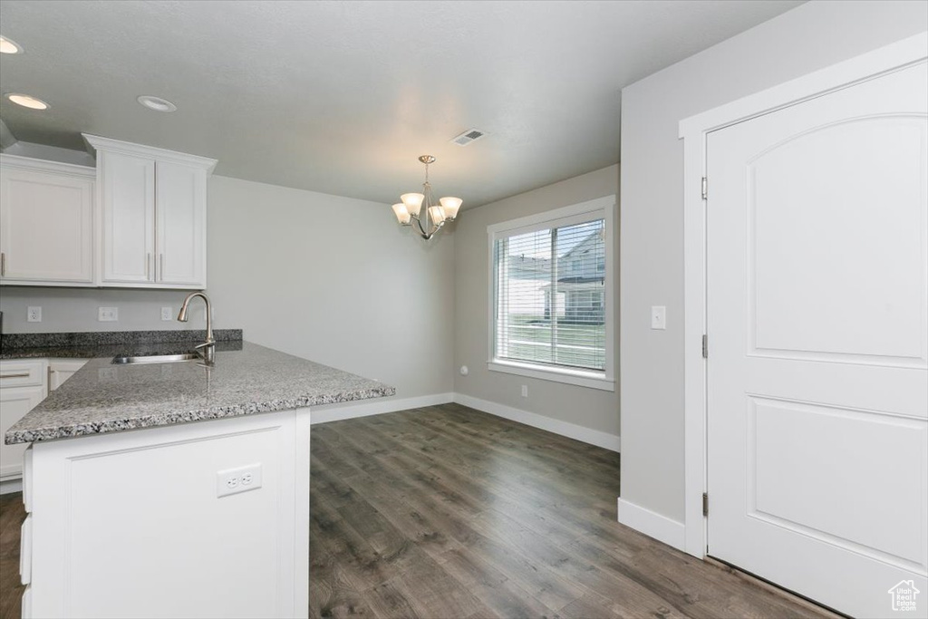 Kitchen featuring a sink, a peninsula, baseboards, white cabinets, and recessed lighting