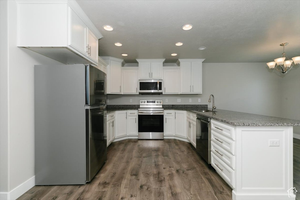 Kitchen with stainless steel appliances, a peninsula, a sink, white cabinetry, and recessed lighting