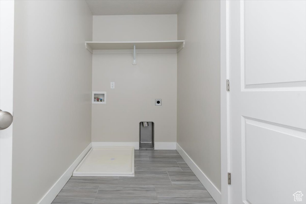 Laundry area with hookup for an electric dryer, hookup for a washing machine, and baseboards