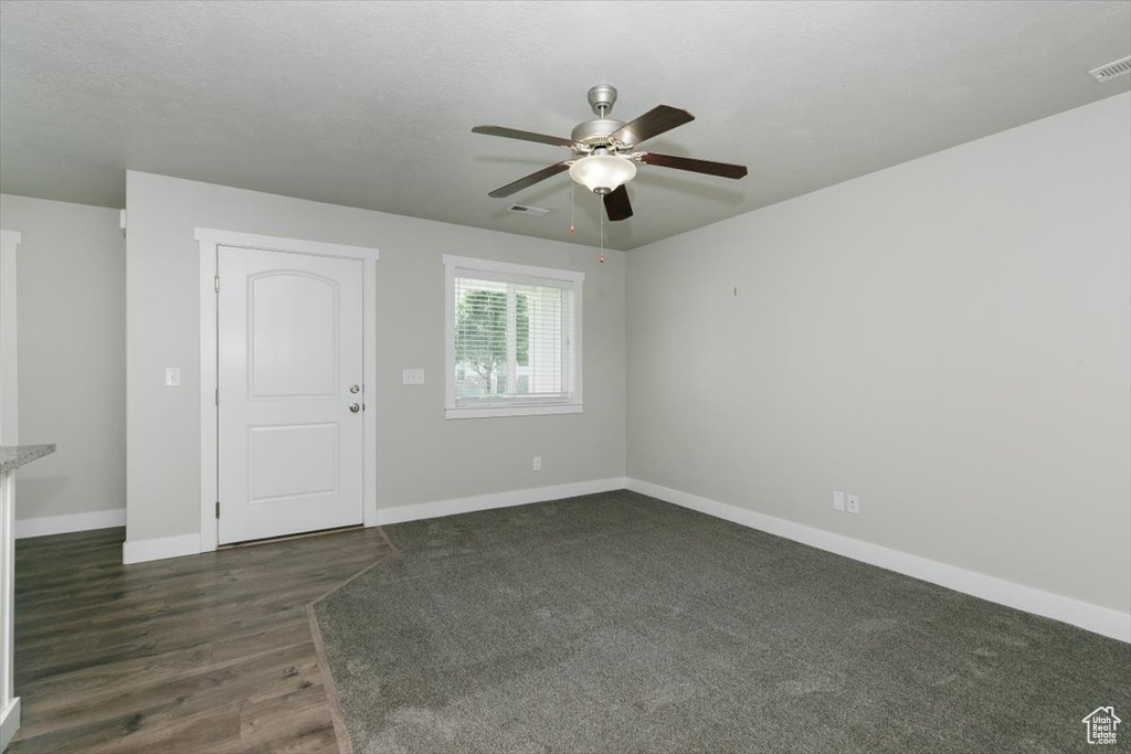 Spare room with ceiling fan, baseboards, and dark wood-style floors
