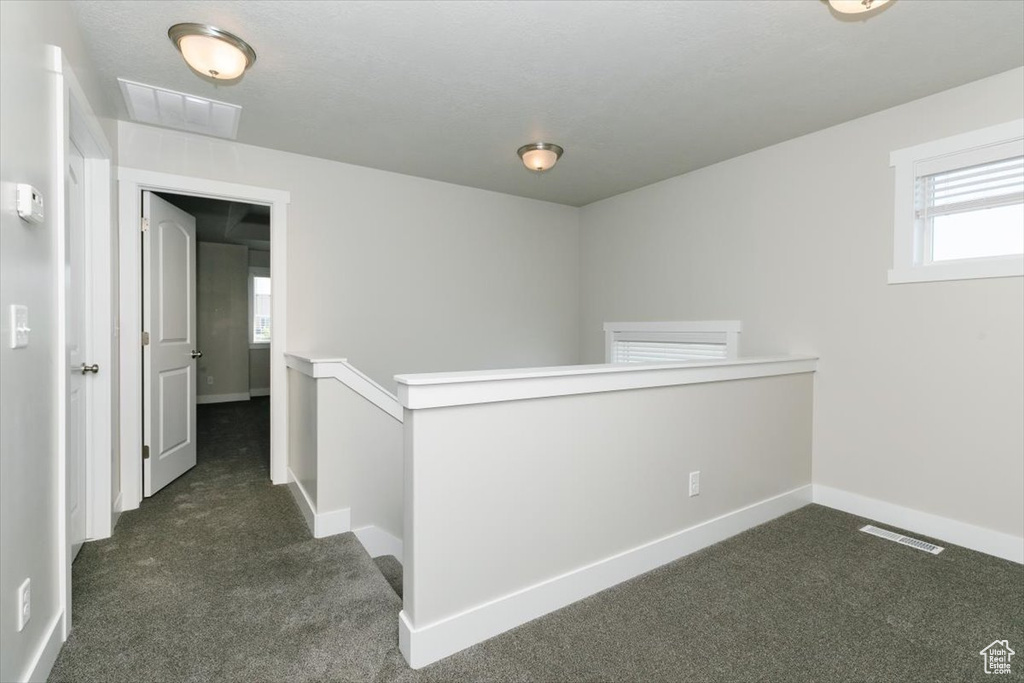 Corridor featuring dark carpet and baseboards