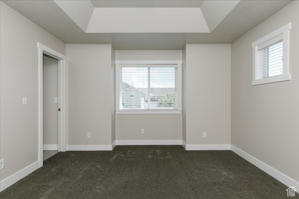 Unfurnished bedroom with dark colored carpet and baseboards