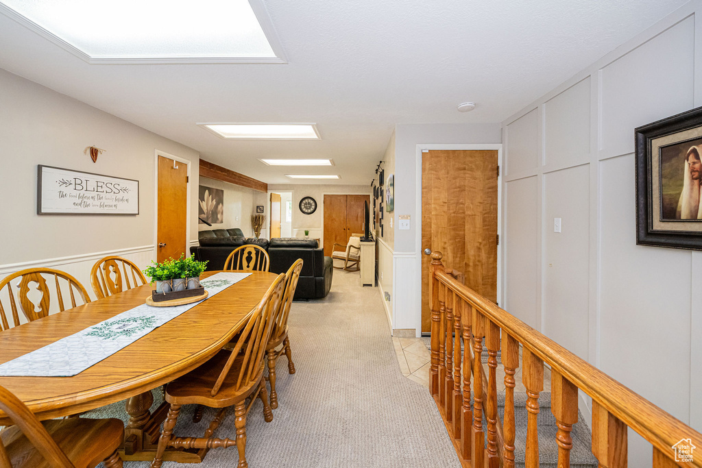 Dining area with a decorative wall, light carpet, and a wainscoted wall