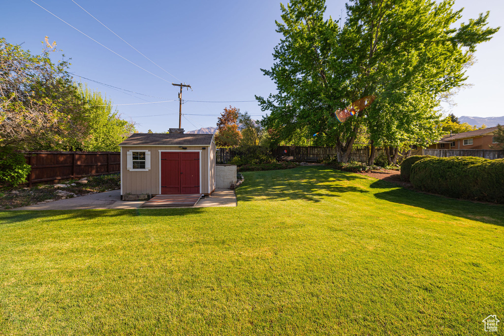 View of yard featuring an outdoor structure, a fenced backyard, and a shed