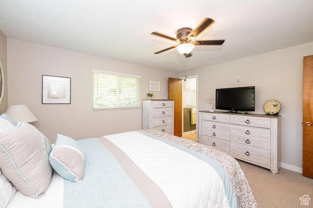 Bedroom with light colored carpet, baseboards, and ceiling fan