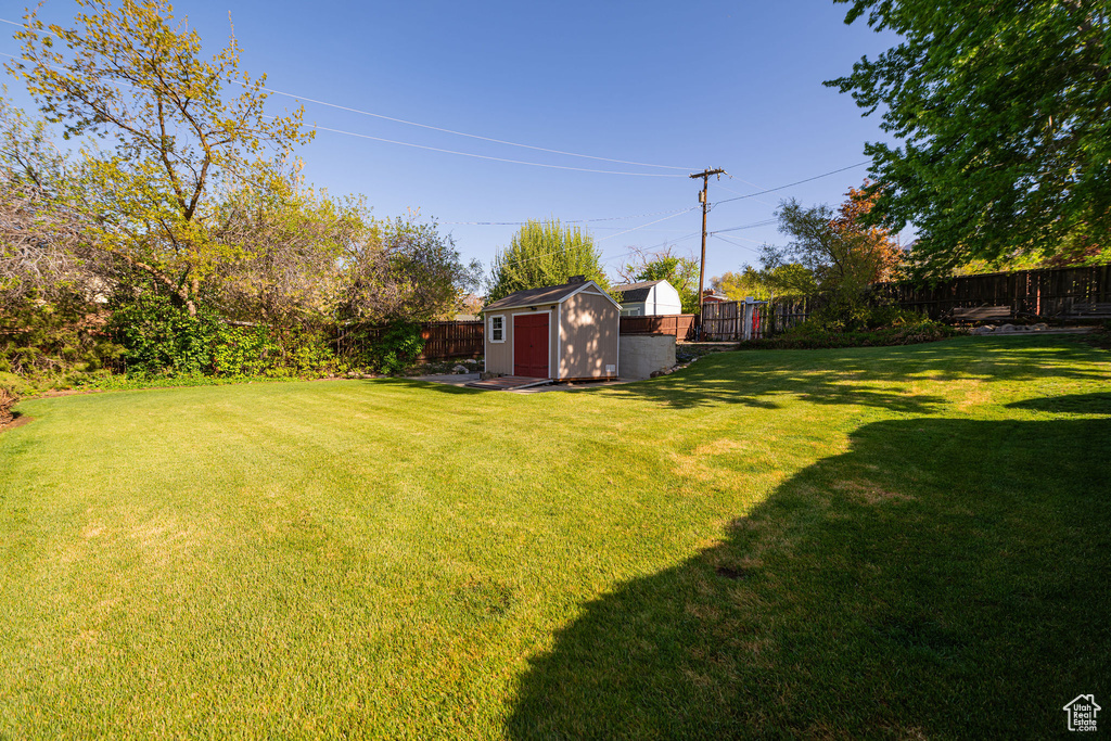 View of yard with an outdoor structure, a fenced backyard, and a shed