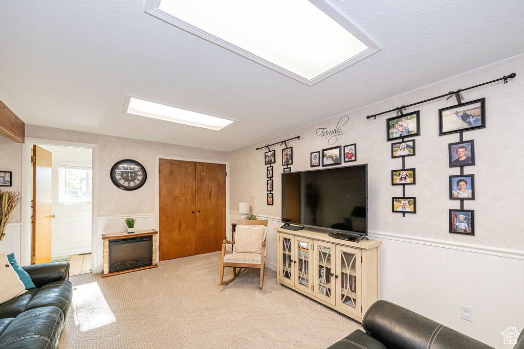 Living area featuring carpet flooring, a wainscoted wall, and a fireplace