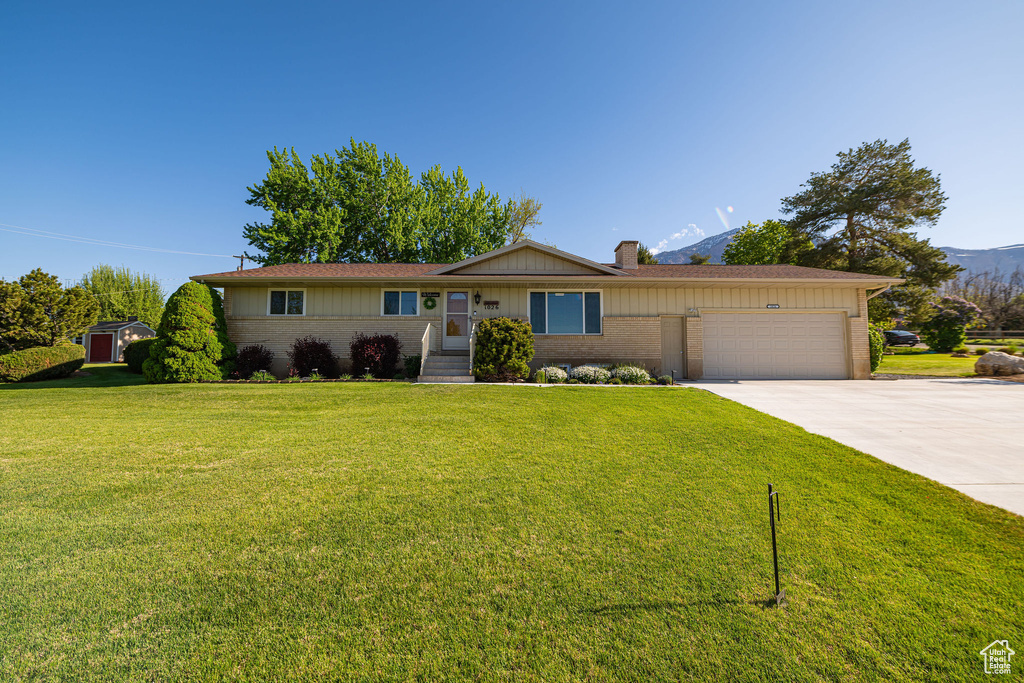 Ranch-style home with concrete driveway, brick siding, board and batten siding, and a garage