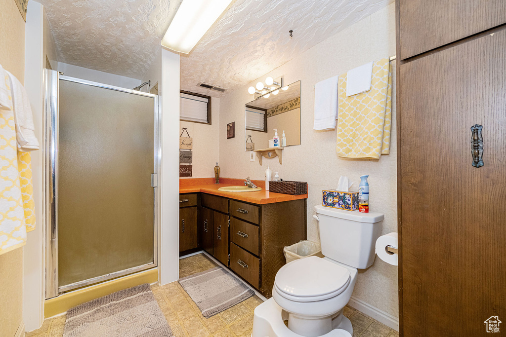 Bathroom featuring vanity, visible vents, toilet, a textured ceiling, and a stall shower