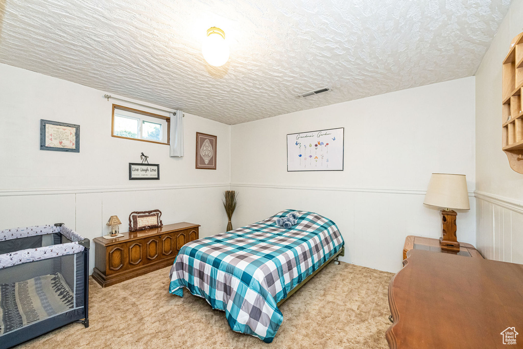 Carpeted bedroom with a textured ceiling and visible vents