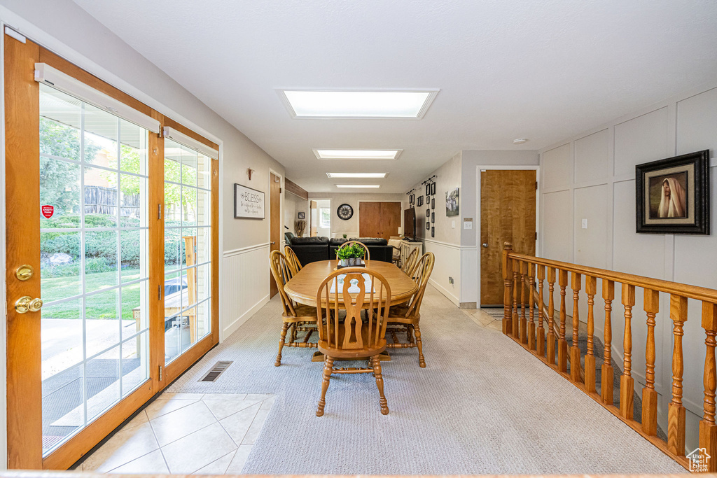 Dining room featuring visible vents, light carpet, and a decorative wall