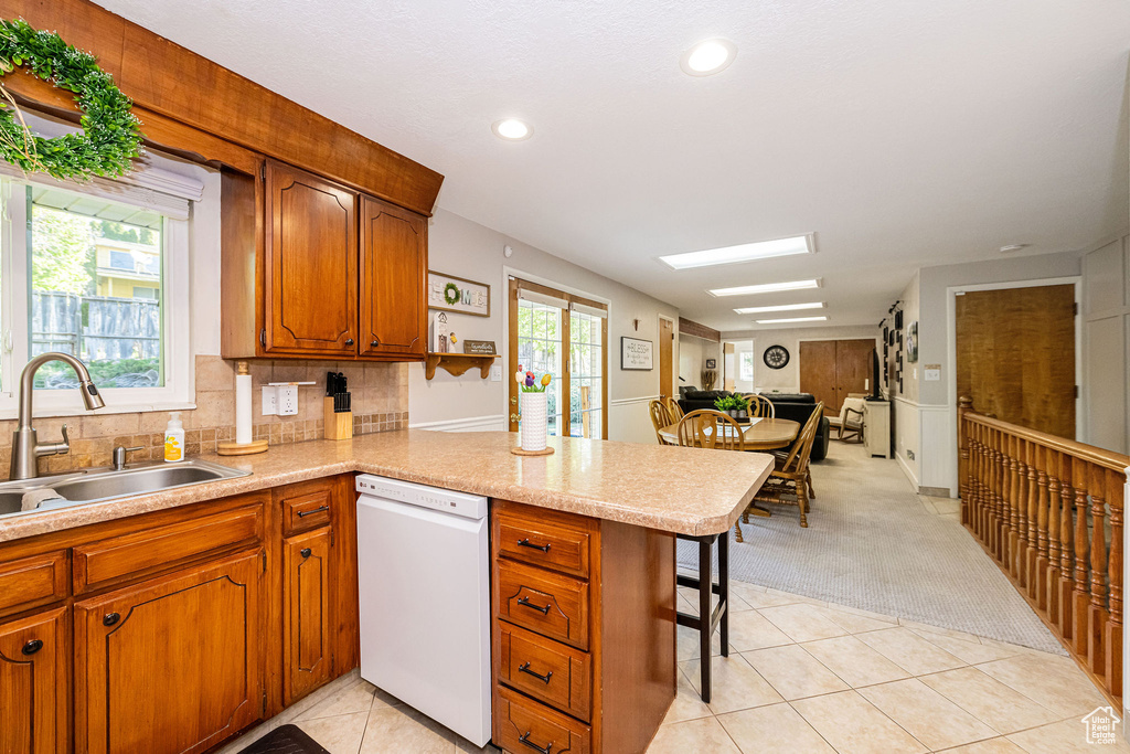 Kitchen with a sink, light tile patterned floors, plenty of natural light, and dishwasher